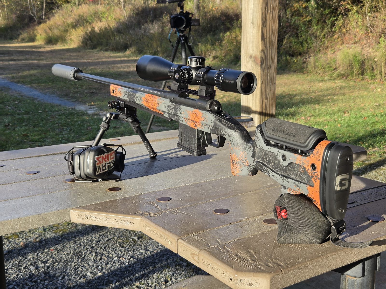Grayboe Core stock in an orange camo finish on a rear bag, with an AICS magazine and bipod-mounted rifle
