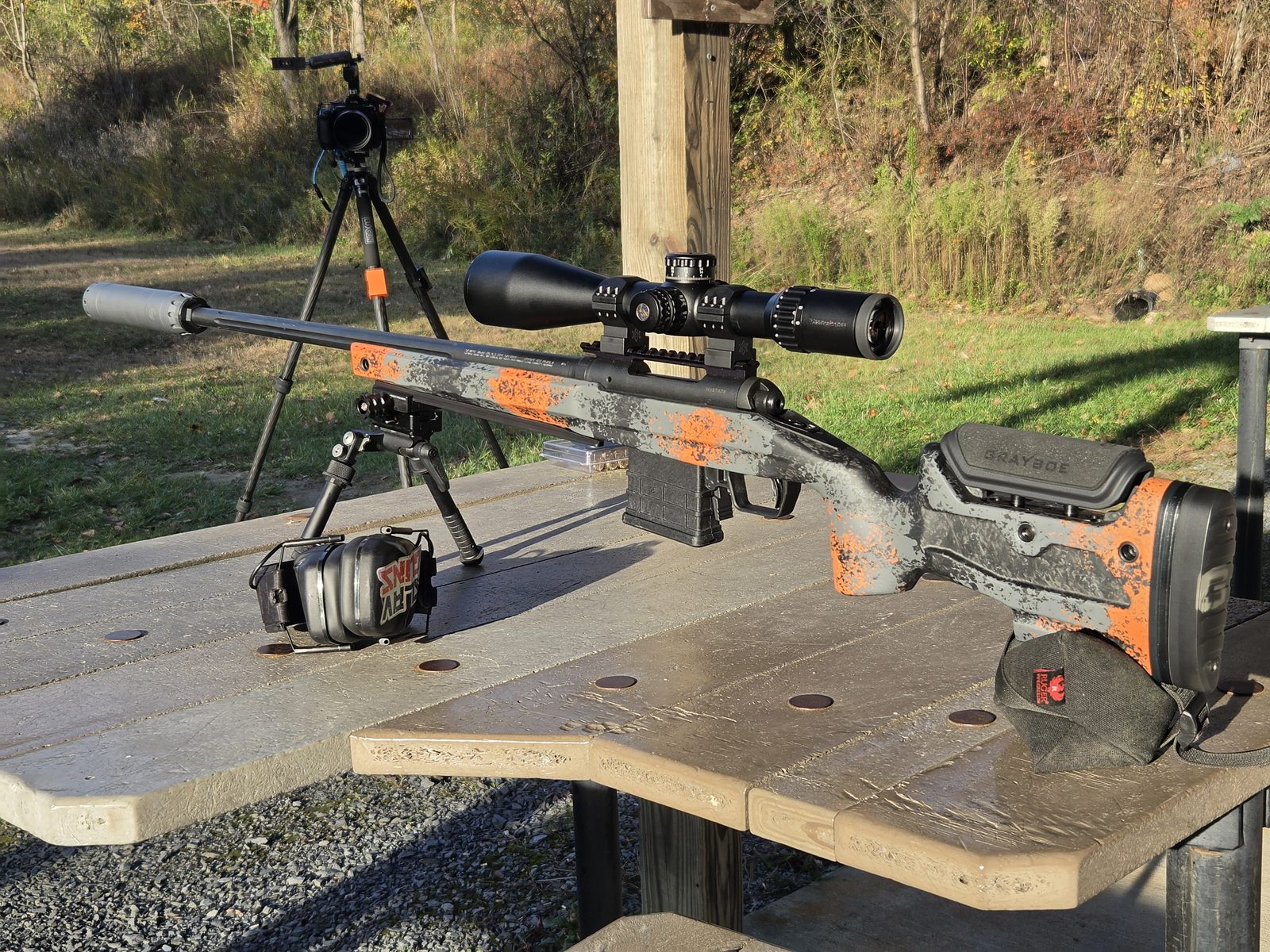 Side view of a scoped, suppressed rifle in a Grayboe Core stock on a range bench